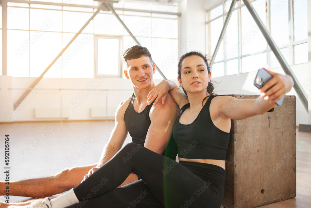 athletic couple in sportswear in training take selfie on smartphone in fitness room, woman and man take pictures