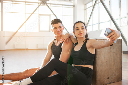 athletic couple in sportswear in training take selfie on smartphone in fitness room  woman and man take pictures