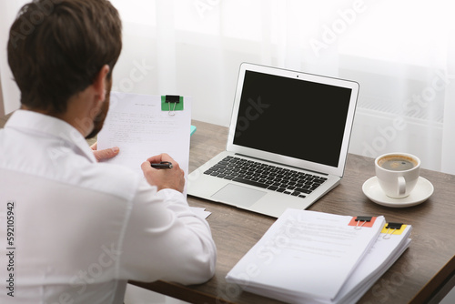 Businessman working with documents at table in office, back view