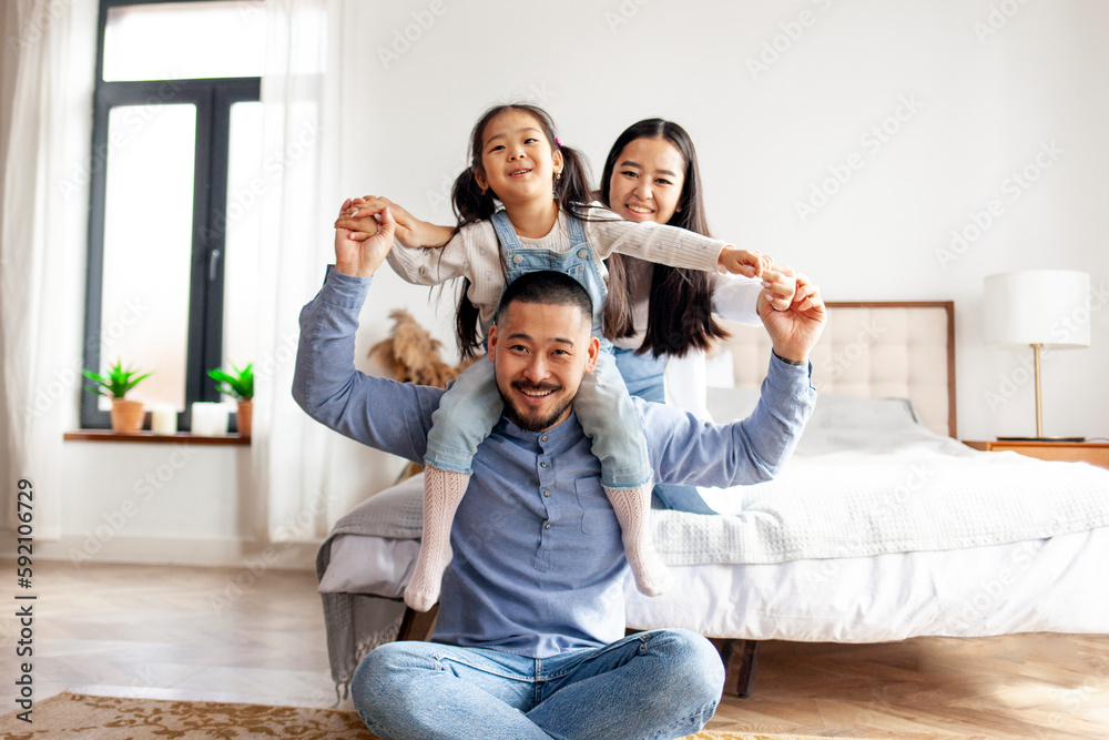 Korean dad holds his little daughter in his arms and depicts flight, child plays with his parents and rejoices at home