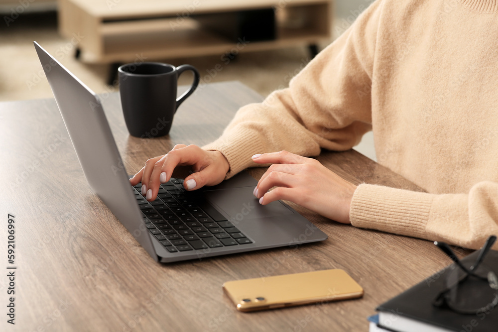 Woman working with laptop at wooden desk indoors, closeup Woman working with laptop at wooden desk indoors, closeup