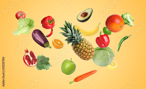 Fototapeta Naklejka Na Ścianę i Meble -  Many fresh vegetables and fruits falling on gold background