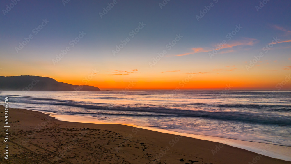Soft hazy sunrise seascape and vibrant crepuscular rays on the horizon