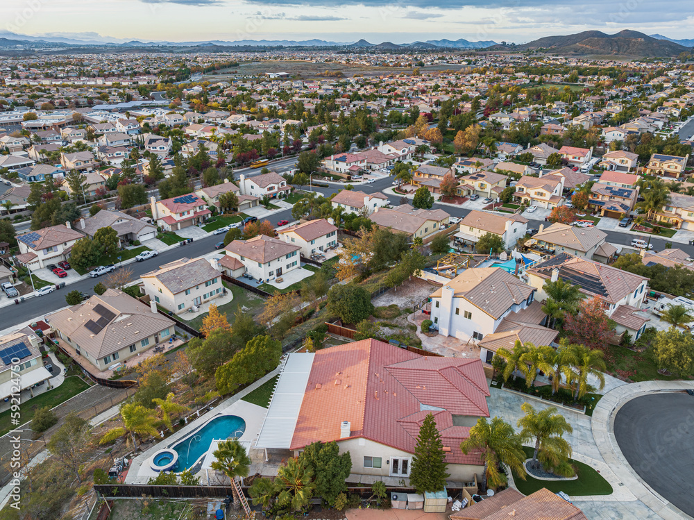 Obraz premium Aerial view of home with pool on a cul de sac street surrounded by luxury single family homes rolling hills in new residential West Coast USA real estate suburban neighborhood dramatic sunset sky