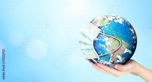 Earth Day concept, Earth wearing a mask on blurred blue nature background. Elements of this image furnished by NASA