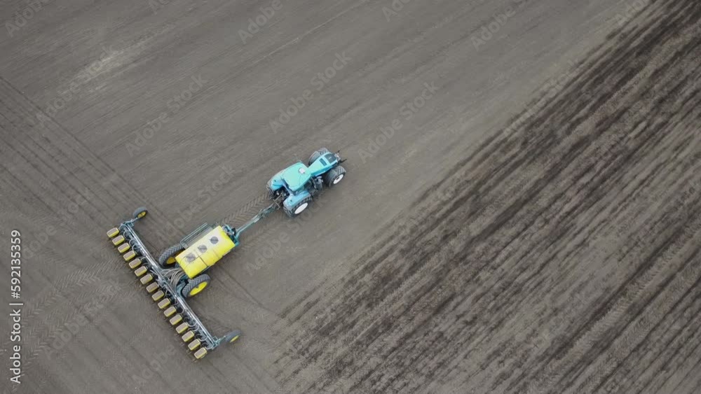 Blue tractor with yellow seeder working on the field in Ukraine OA Blue tractor with yellow seeder working on the field in Ukraine OA