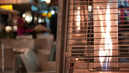 Static shot of a fire pit - street gas heater on street filled with bars and terraces photo
