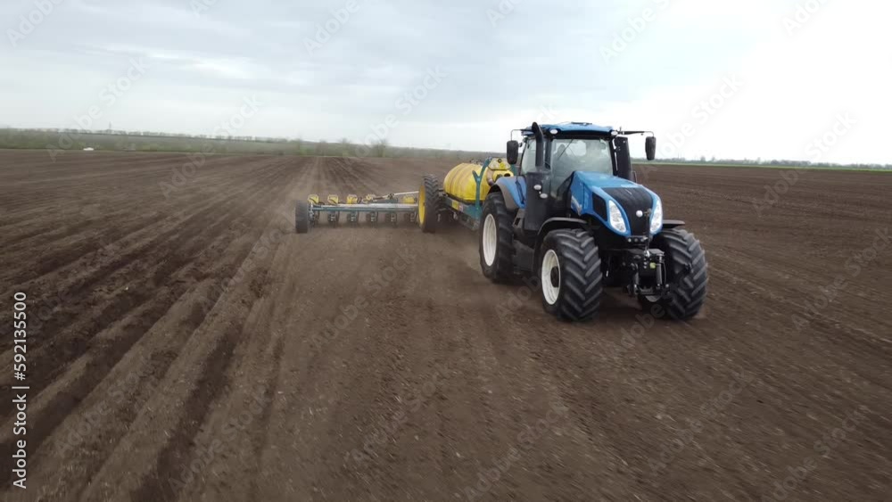 Blue tractor with yellow seeder working on the field in Ukraine OA Blue tractor with yellow seeder working on the field in Ukraine OA