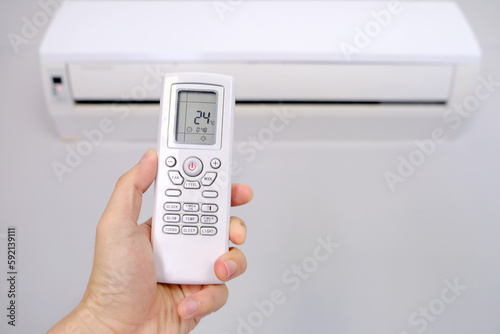 Man's hand using remote control open The air conditioner is cooled to 24 degrees Celsius in his bedroom. Health concepts and energy savings
