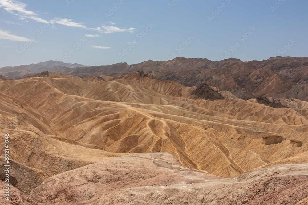 Naklejka premium Scenic view of Badlands of Zabriskie Point, Furnace creek, Death Valley National Park, California, USA. Erosional landscape of multi hued Amargosa Chaos rock formations, Panamint Range in the back