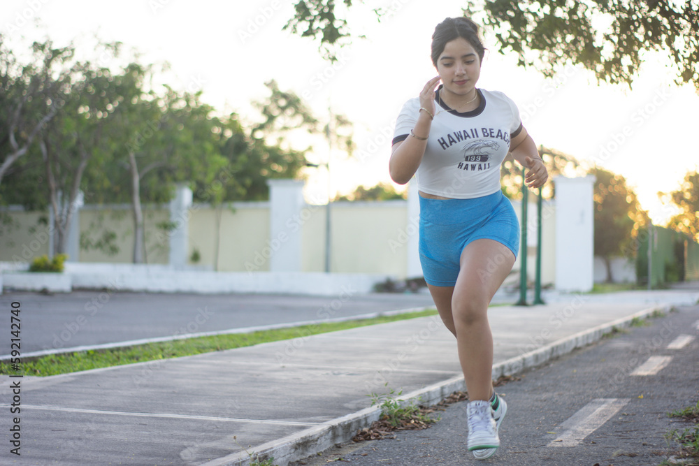 A latin teenager woman starts to training at the park at sunrise A latin teenager woman starts to training at the park at sunrise