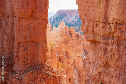 Scenic view through window of narrow massive steep hoodoo sandstone rock formation towers on natural amphitheatre in Bryce Canyon National Park, Utah, USA. Queens Garden loop hiking trail in summer