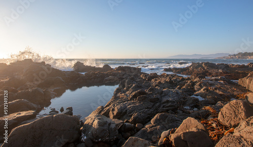 Sunlight on wave spray on rocky central California coastline during golden hour at Cambria California United States