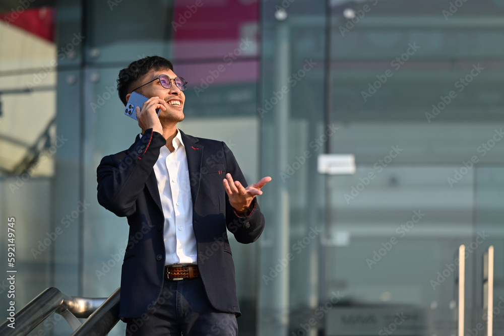 Portrait of handsome businessman wearing elegant suit talking on mobile phone at outdoors in urban modern city Portrait of handsome businessman wearing elegant suit talking on mobile phone at outdoors in urban modern city