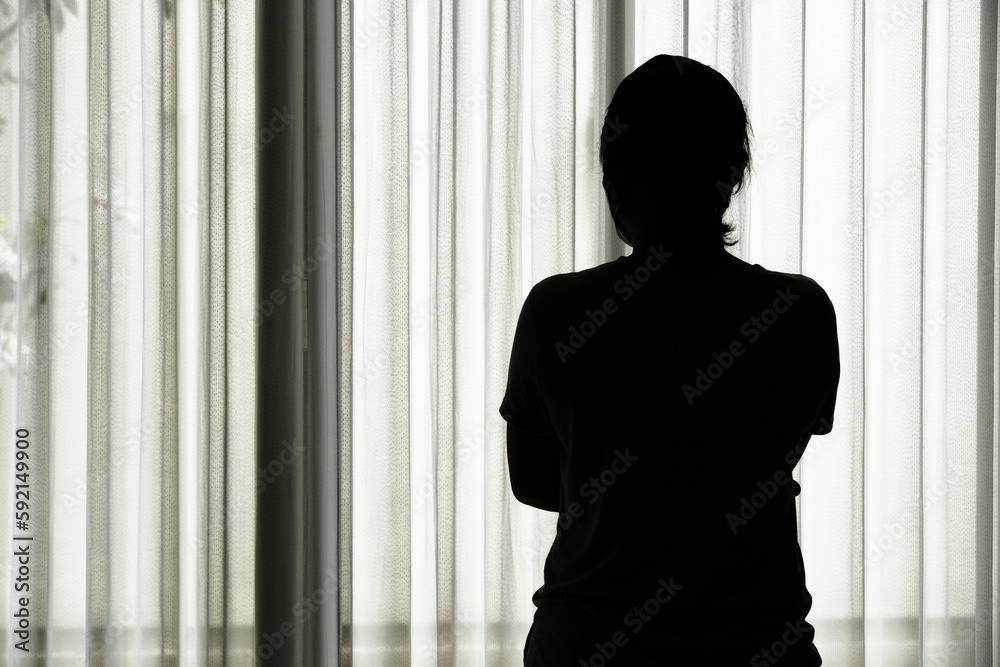 Silhouette of a woman standing by the window.