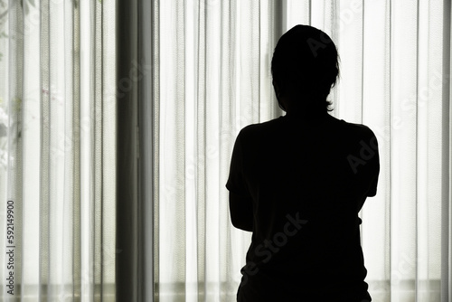Silhouette of a woman standing by the window. photo