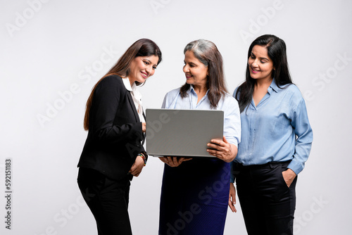 senior female executive showing detail in laptop to his two young colleague.