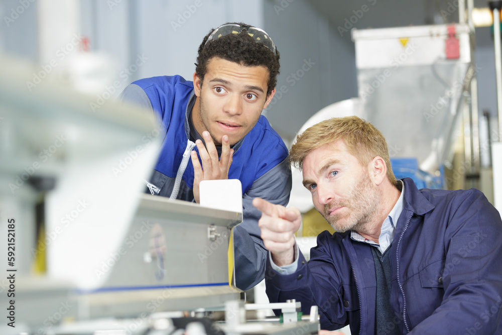 two men working on a machine two men working on a machine
