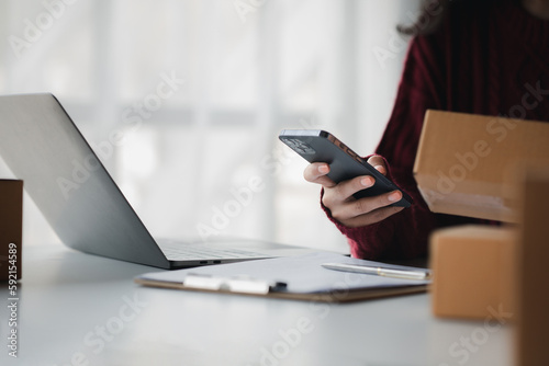 Person looking at customer information on a mobile phone, selling products online, packing orders from customers who place orders through online shopping sites. Selling products online and e-commerce.