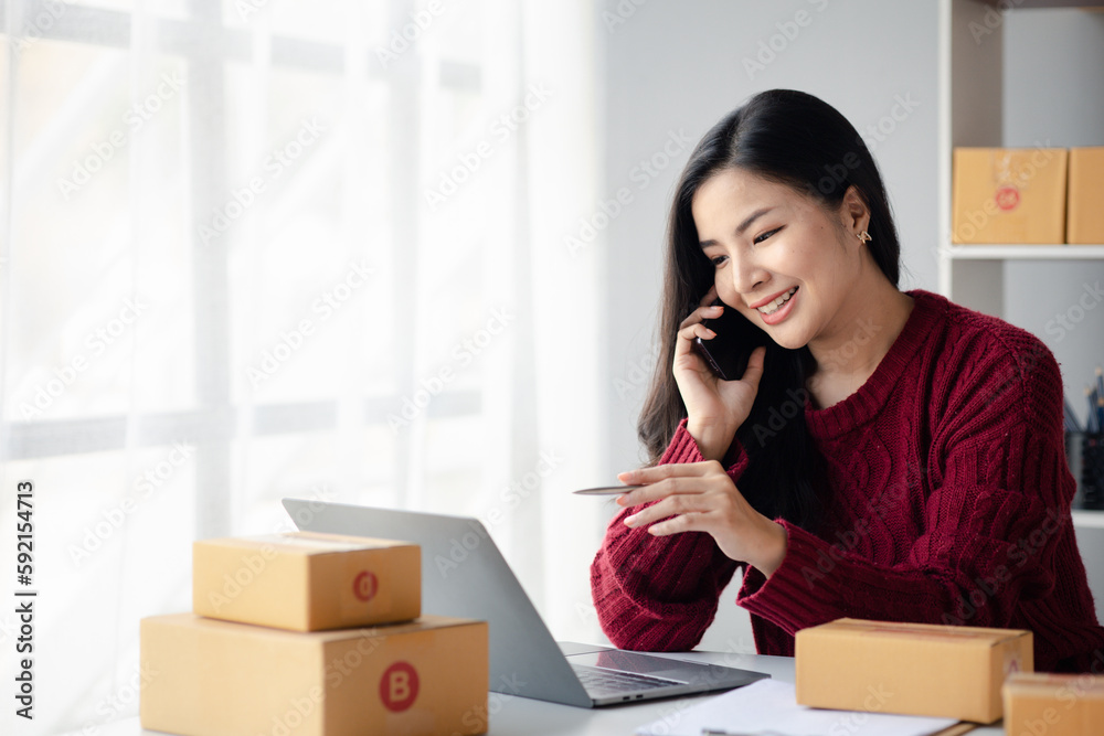 Person is talking on the phone with a customer, selling products online, packing orders from customers who place orders through online shopping sites. Concept of selling products online and e-commerce Person is talking on the phone with a customer, selling products online, packing orders from customers who place orders through online shopping sites. Concept of selling products online and e-commerce