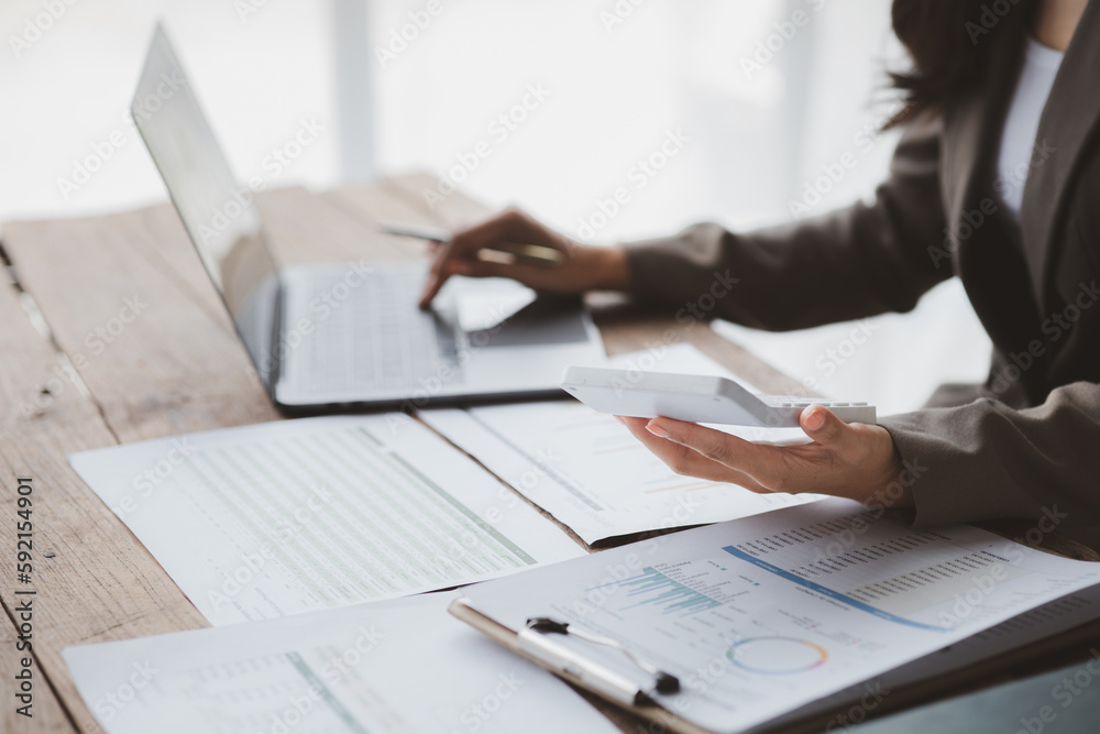 Businessman using a calculator to calculate numbers on a company's financial documents, she is analyzing historical financial data to plan how to grow the company. Financial concept. Businessman using a calculator to calculate numbers on a company's financial documents, she is analyzing historical financial data to plan how to grow the company. Financial concept.