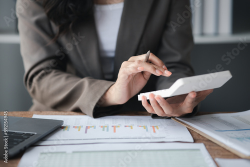 Businessman using a calculator to calculate numbers on a company's financial documents, she is analyzing historical financial data to plan how to grow the company. Financial concept.