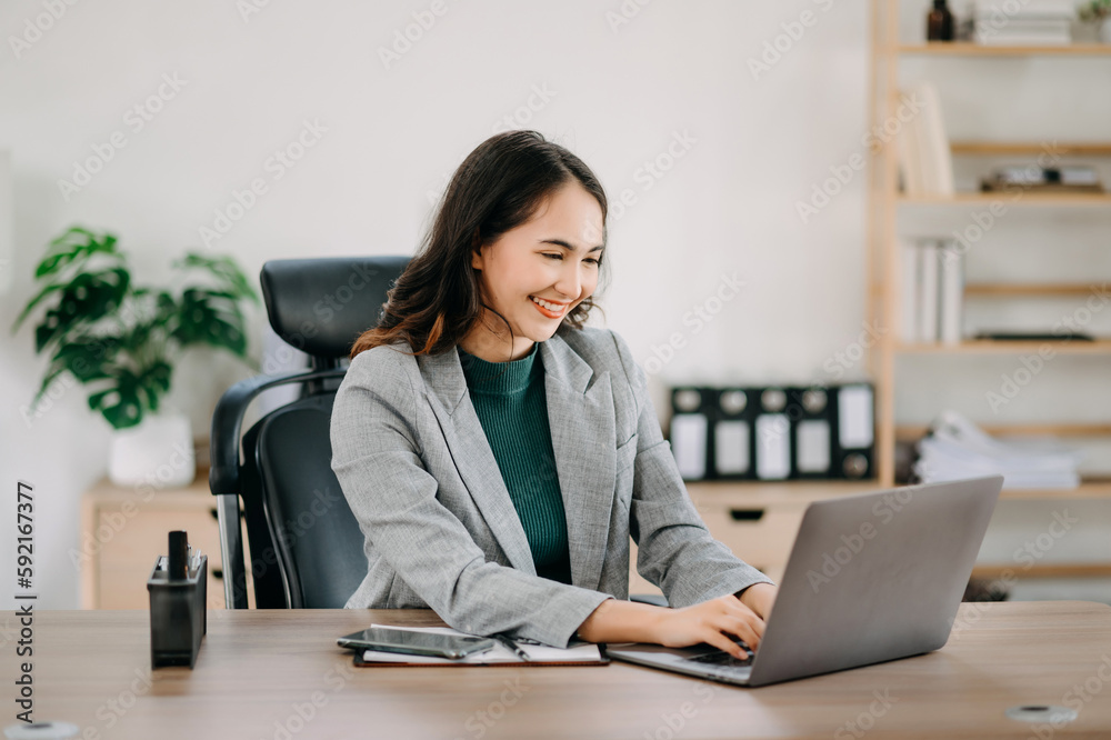 Beautiful Asian woman using laptop and tablet while sitting at her working place. Concentrated at work.. Beautiful Asian woman using laptop and tablet while sitting at her working place. Concentrated at work..