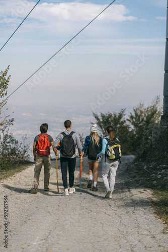 A back view photo of two couples hiking in the mountain. They are walking on a small steret