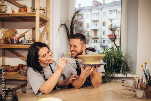 Canvas Print Mid adult couple smiling while doing creative painting on bowls in pottery works