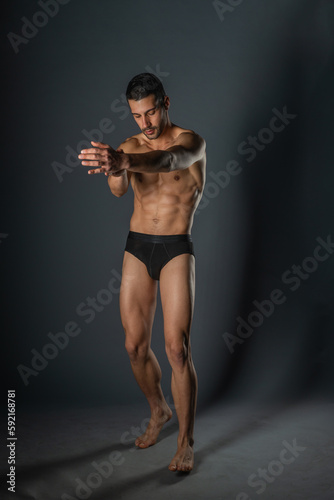 Naked young sexy man posing in black underwear in a studio