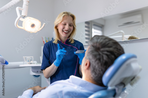 Pretty dentist doctor woman showing jaw model at dental clinic  dental care concept. Dental care concept. Young woman dentist showing male patient jaw model at dental clinic