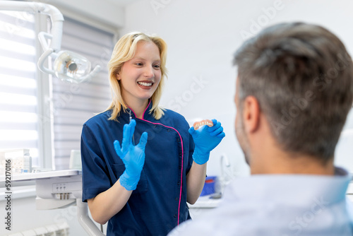 Dentist showing dental plaster mold to the patient. Dentist doctor showing jaw model at dental clinic, dental care concept. Dental care concept.