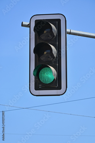 Traffic light with a lit green light on a background of a blue sky