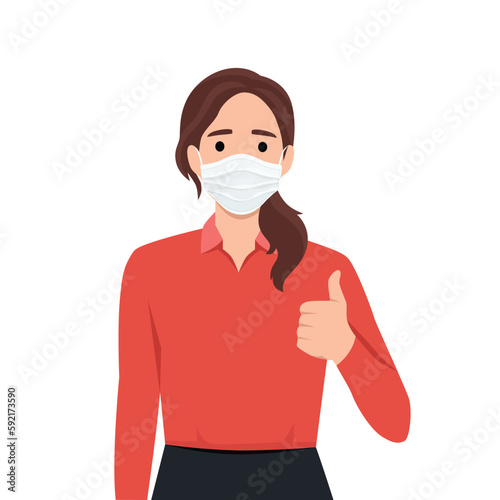 Happy young woman wearing medical face mask and showing thumbs up sign. Trendy girl covering protective surgical mask and gesturing good, success symbol