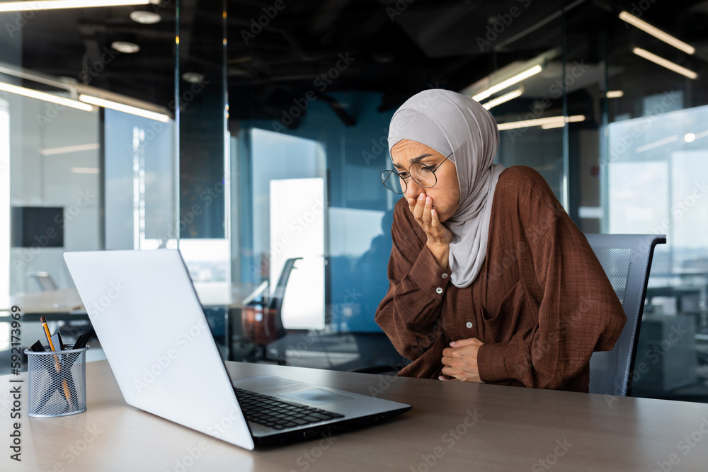 Sick business woman in hijab working inside office at workplace, nausea