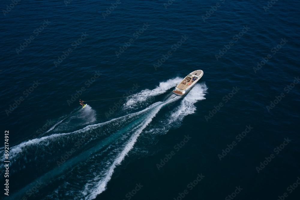 Aerial view of a man wakeboarding on the water. Water skiing on the water behind the boat.