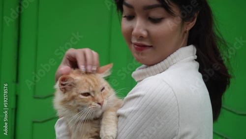 A beautiful Asian woman is carrying her orange Angora cat photo