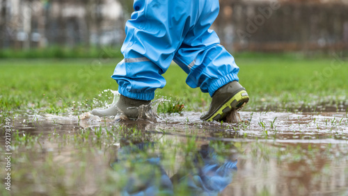 Cutout of a young child in park having fun in a puddle during rainy weather