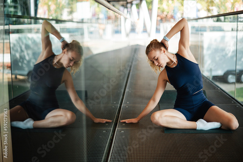 Young female athlete in sportswear exercising and stretching body