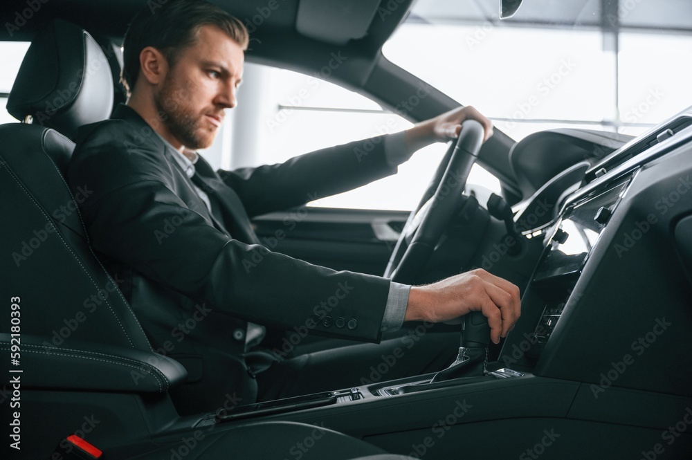 Man in formal business clothes is sitting in the modern automobile Man in formal business clothes is sitting in the modern automobile