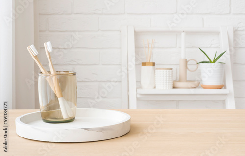 Bamboo toothbrushes in glass on wooden table with copy space