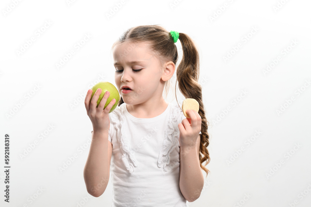 Green apple and potato chips, healthy and unhealthy food for kids, little girl chooses apple over chips. Green apple and potato chips, healthy and unhealthy food for kids, little girl chooses apple over chips.