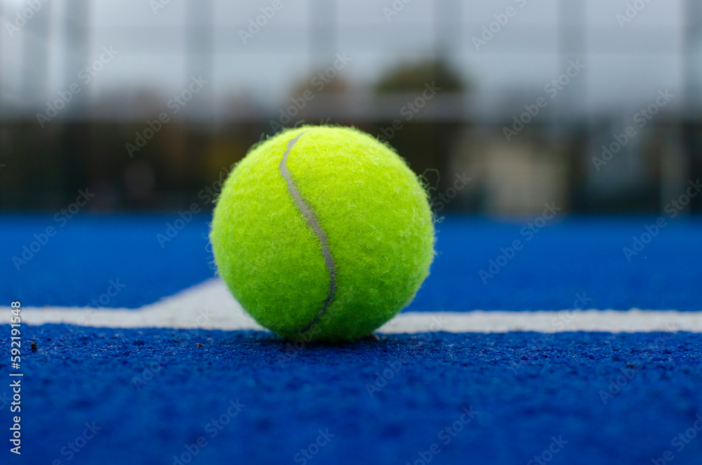 close-up view of a ball on the lines of a blue paddle tennis court, racket sports