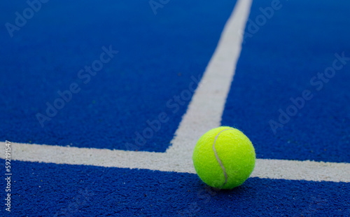close-up view of a ball on the lines of a blue paddle tennis court, racket sports concept © VicVaz