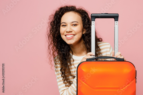 Traveler smiling woman wear light casual clothes hold suitcase isolated on plain pastel pink background studio. Tourist travel abroad in free spare time rest getaway. Air flight trip journey concept.