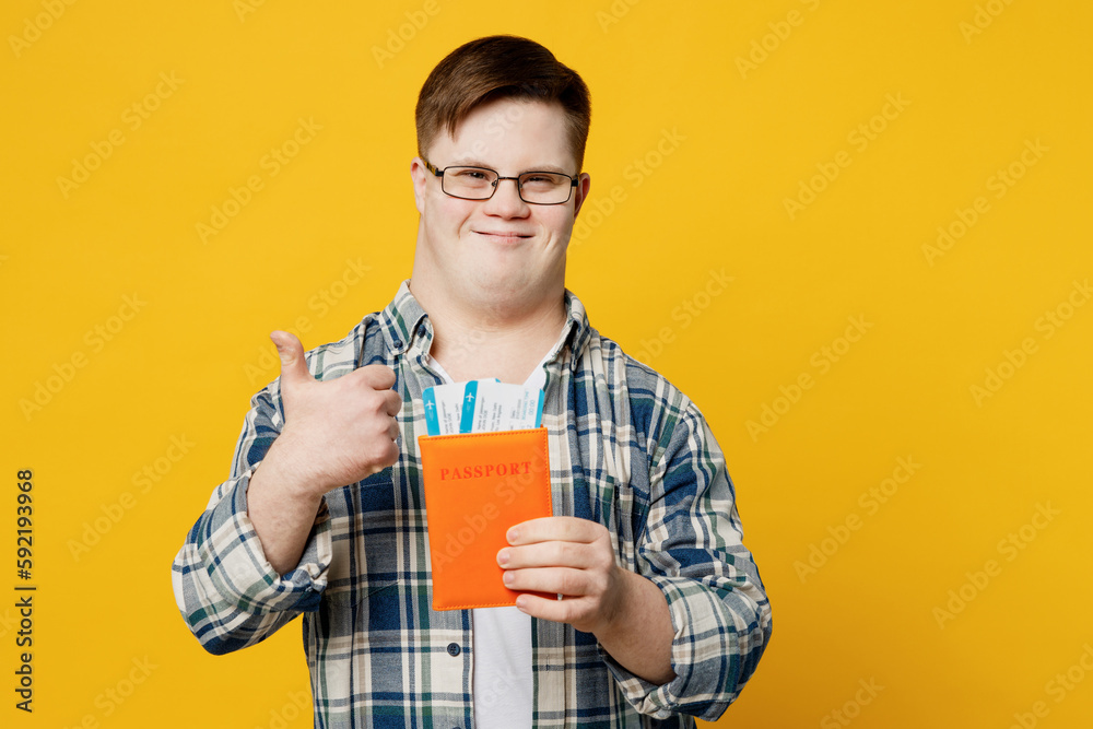 Traveler man with down syndrome wears casual clothes hold passport ticket isolated on plain yellow background. Tourist travel abroad, rest getaway. Air flight trip, genetic disease world day concept. Traveler man with down syndrome wears casual clothes hold passport ticket isolated on plain yellow background. Tourist travel abroad, rest getaway. Air flight trip, genetic disease world day concept.