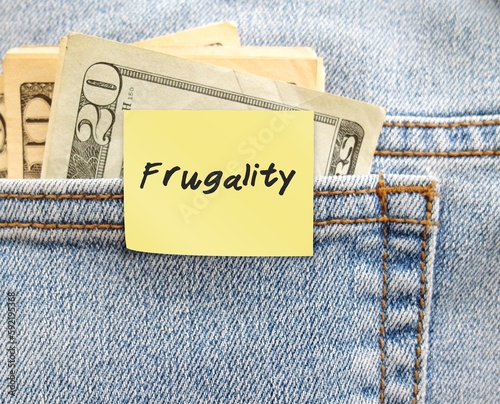 Money in jeans pocket with handwritten note FRUGALITY, latest trend In Work-Life Balance - accepting lower pay for less-demanding job - Living more frugally to leave stressful job photo