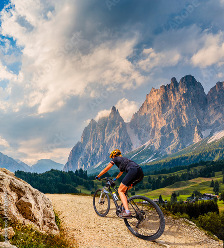 Woman ride electric mountain bikes in the Dolomites in Italy. Mountain biking adventure on beautiful mountain trails. © Gorilla