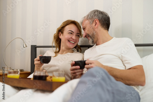 Mature couple enjoying coffee and breakfast in bed