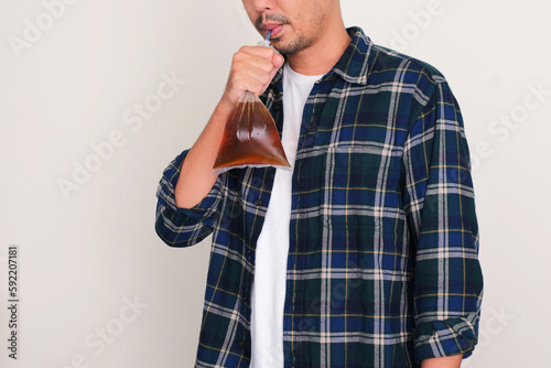 Adult man drink an ice tea from plastic bag with straw